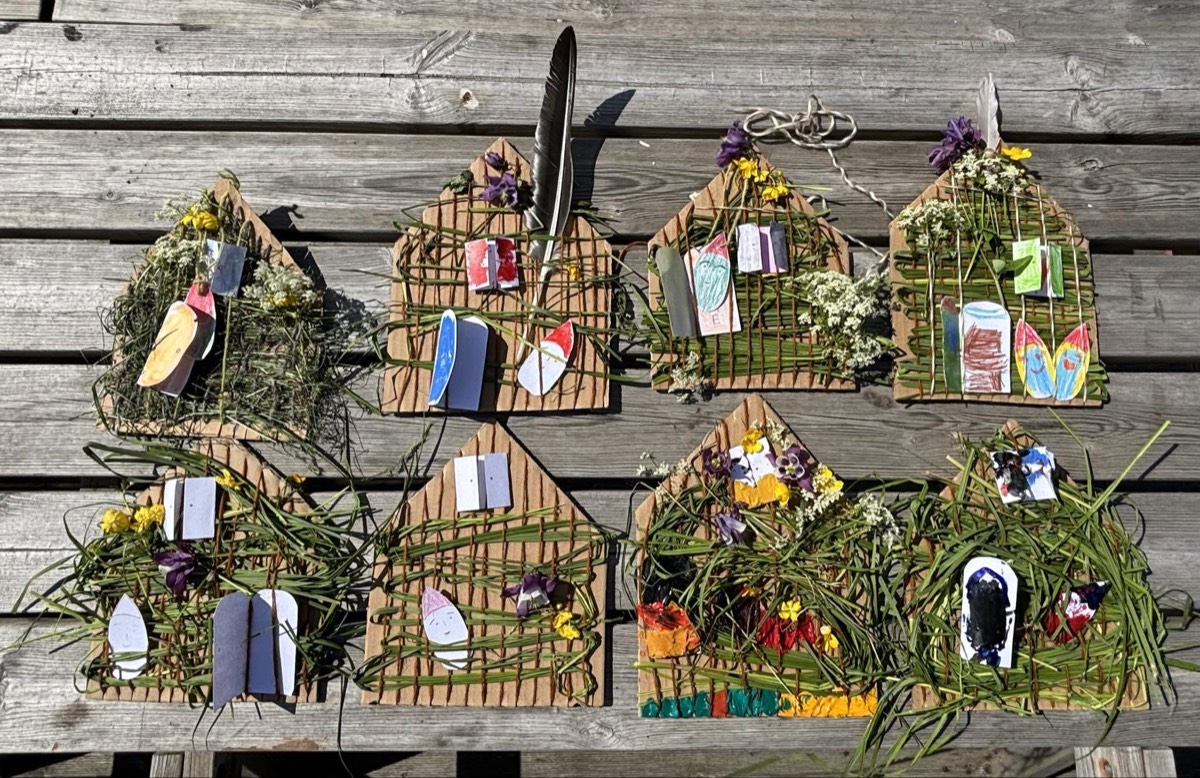 Eight small woven houses made from grass, flowers and card
